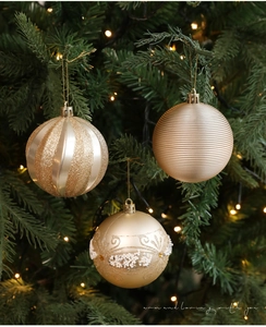 Dettaglio di palline di Natale dorate da 8cm con glitter e perle su un albero festivo