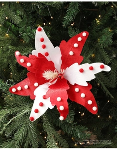 Detailed view of red and white star ornament with bells on a lighted Christmas tree