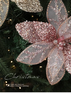 Close-up of glittered mesh Christmas flowers in champagne gold on a festive pine tree