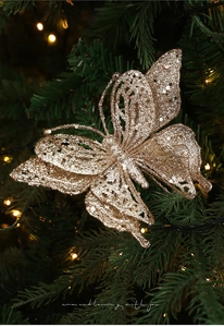Close-up of golden glitter butterfly ornament with hollow pattern on Christmas tree branch