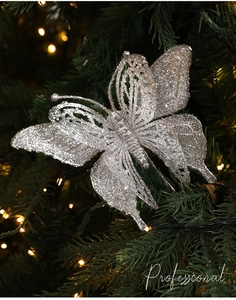 Detailed view of a silver glitter butterfly ornament on a green Christmas tree branch