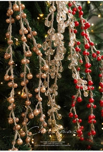 Dettaglio rami decorativi natalizi con bacche color oro champagne, cristallo e rosso