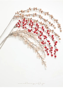 Dettaglio macro di rami natalizi con bacche di perle rosse, oro e cristallo trasparente