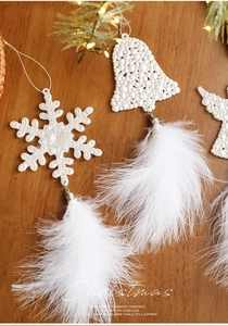 Close-up of white snowflake ornament with pearl textures and soft hanging feathers