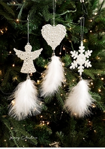 Detail of white pearl snowflake and angel ornaments with feathers on Christmas tree