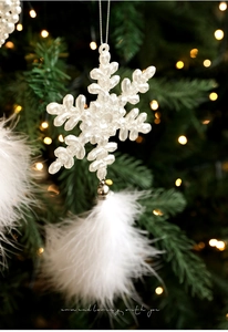 Close-up of white snowflake ornament with soft feather fringe on a Christmas tree