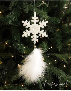 Close-up of snowflake Christmas ornament with white feathers hanging on a tree