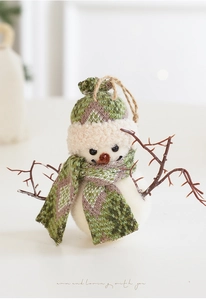 Détail de bonhomme de neige en peluche avec bonnet tricoté vert et bras en branche