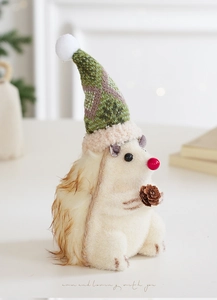 Détail d'un hérisson de Noël en peluche tenant une pomme de pin sur une table décorée