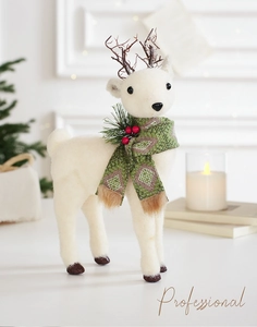 Gros plan d'une figurine de renne blanche avec écharpe verte et détails de pomme de pin