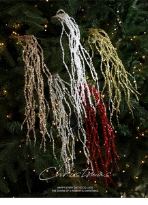 Glittery Christmas spray branch with hanging sequins on a tree with warm lights