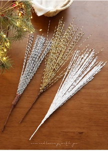 Macro detail of glittered Christmas branches in gold and silver on a wooden table