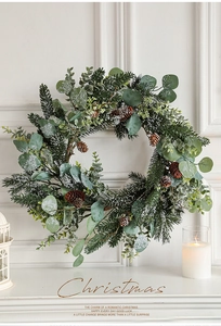Close-up of frosted eucalyptus leaves and pine cones on a Christmas garland with warm candle