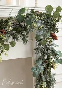 Detail of snowy eucalyptus garland with pine cones on a fireplace mantel