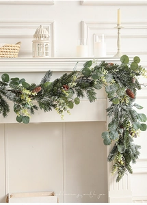Close-up of snowy Christmas garland with pine cones and eucalyptus on a white mantel