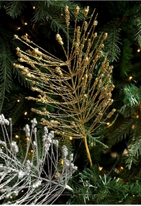 Close-up of sparkling gold glitter branch ornaments on a Christmas tree with warm lights