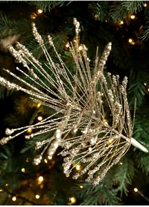 Close-up of golden glitter branch ornaments with fireworks tassel on a Christmas tree