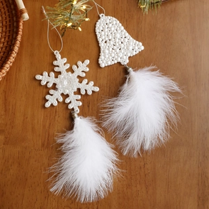 White feather and pearl snowflake bell Christmas tree ornaments set on wooden background