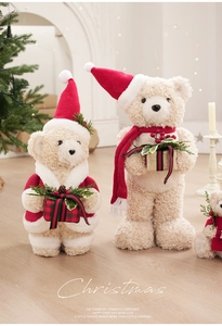 Close-up of beige teddy bears in red Santa outfits holding festive Christmas gift boxes