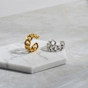 Detailed shot of gold and silver cuban chain rings on a white marble display pedestal