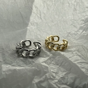 Detail of adjustable S925 silver and gold cuban chain rings on textured paper