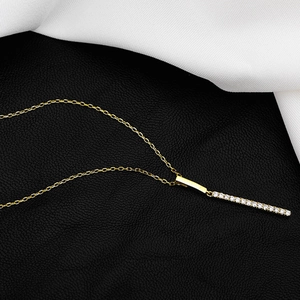 Detailed view of minimalist gold bar necklace with shimmering pavé diamonds on leather