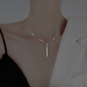 Close-up of a silver bar pendant necklace with micro-pave crystals on a female model