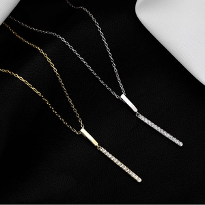 Elegant bar pendant necklace with pavé diamonds in gold and silver finish on a leather background