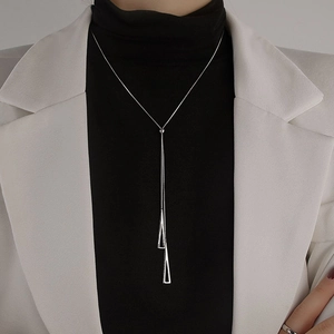 Detail of silver geometric Y-shaped lariat necklace on a model with white blazer