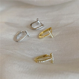 Detailed close-up of T-shaped earrings with micro-pave crystals in gold and silver finish