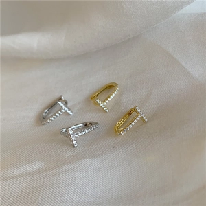 Macro shot of silver and gold T-shaped earrings with micro-pave cubic zirconia inlay