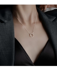 Detail van minimalistische S925 zilveren cirkelketting gedragen op een zwarte blazer jas