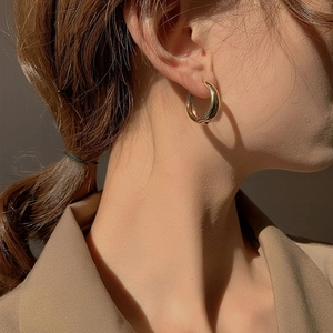 Close-up of elegant gold hoop earring on model showing sleek polished metal texture