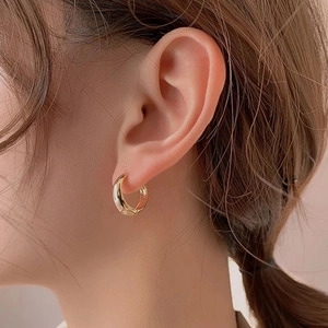 Close-up of chunky gold hoop earrings with a polished mirror finish on the model