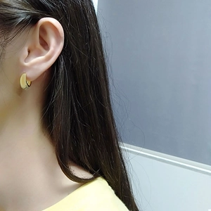 Detail showing thick gold hoop earrings worn by a model in a minimalist style