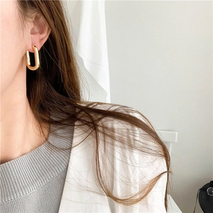 Close-up of minimalist gold U-shape geometric drop earrings worn by a model