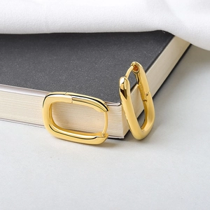 Detail shot of golden rectangular hoops showing S925 hallmark on polished metal surface