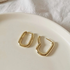 Macro shot showing gold rectangular hoop earrings with open and closed secure clasps