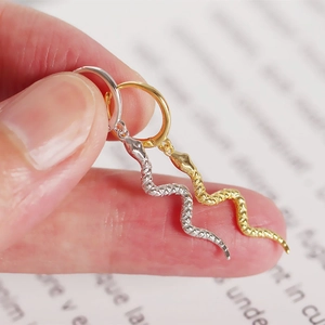 Detail shot of gold and silver snake earrings featuring textured scales on ear hoops