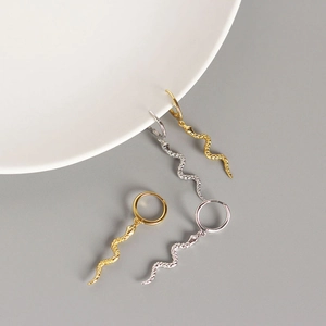 Detailed view of gold and silver snake drop hoop earrings with textured scale finish