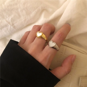 Detail view of gold and silver heart rings with mother of pearl inlay and beaded edges