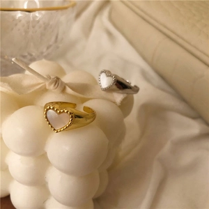 Detail of gold and silver heart rings with pearl inlay and bead trim on white decor