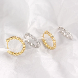 Macro shot of silver and gold paved zircon hoop earrings on a textured paper background