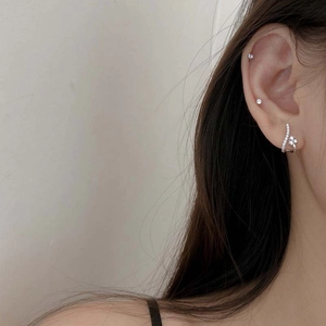 Gros plan sur d'élégantes boucles d'oreilles argentées courbées avec cristaux floraux