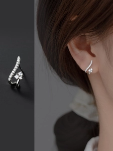 Détail de boucles d'oreilles courbes en argent avec zircons brillants sur modèle
