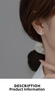 Détail d'un clou d'oreille argenté courbé avec des zircons brillants sur l'oreille