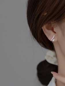 Gros plan de boucles d'oreilles courbées en argent avec diamants étincelants