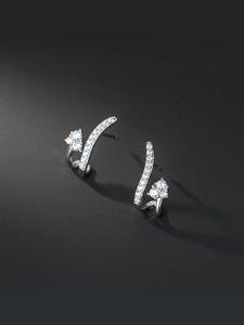 Détail macro de boucles d'oreilles argentées incurvées avec zircons ronds brillants