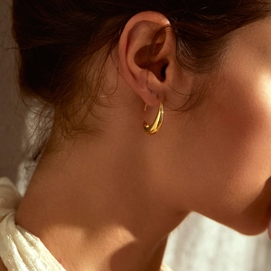 Close-up of sleek gold crescent moon earrings worn by model for a modern minimalist look