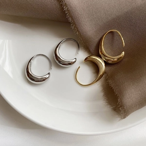 Detailed view of polished silver and gold teardrop earrings on minimalist background
